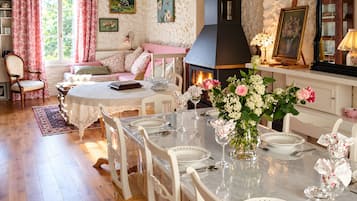 A cozy dining area with a fireplace, floral decorations, and a comfortable seating arrangement.