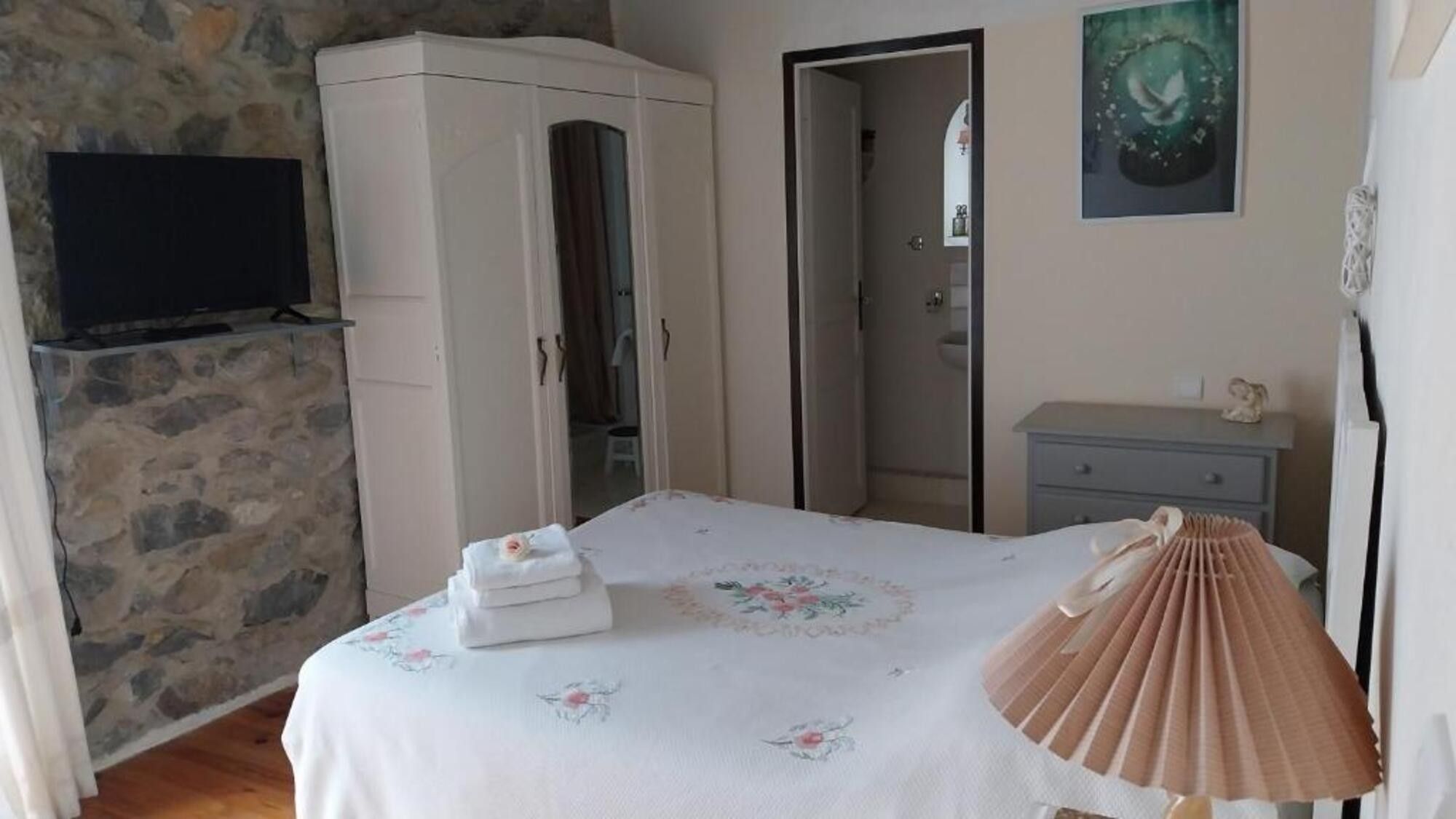 Une chambre à coucher avec un lit, une armoire, un téléviseur, une porte et un tableau au mur.