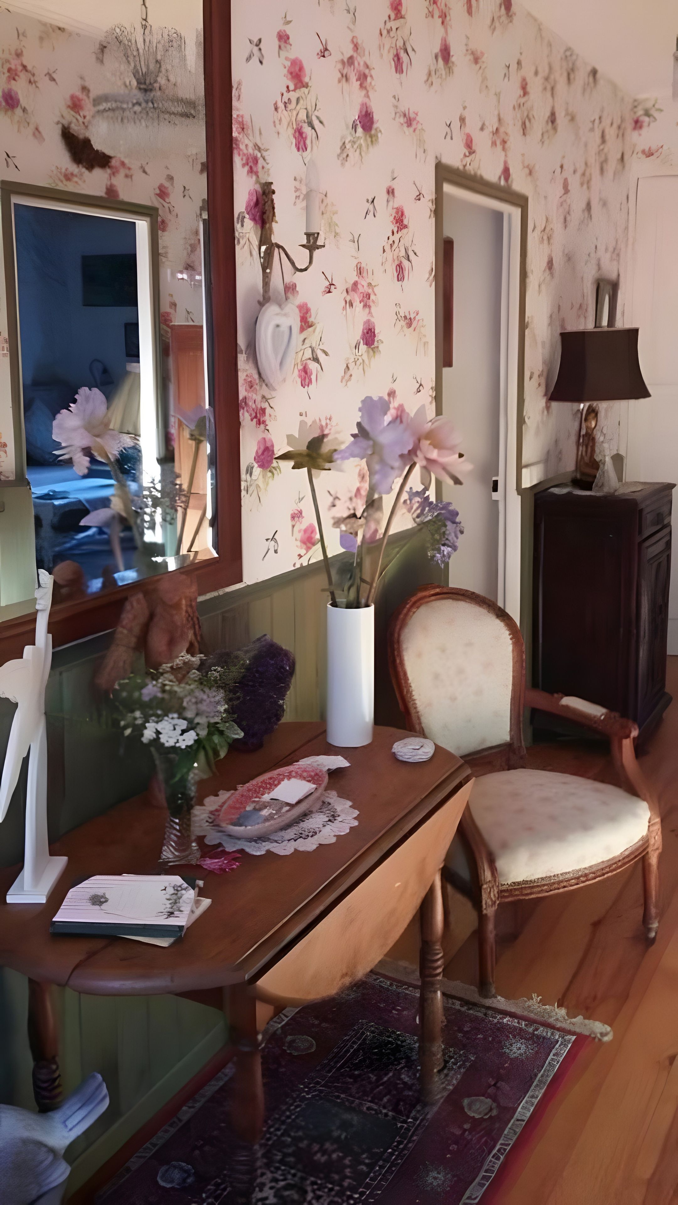 Une pièce comprenant une table à manger, des chaises, un vase avec des fleurs, un miroir et un meuble.