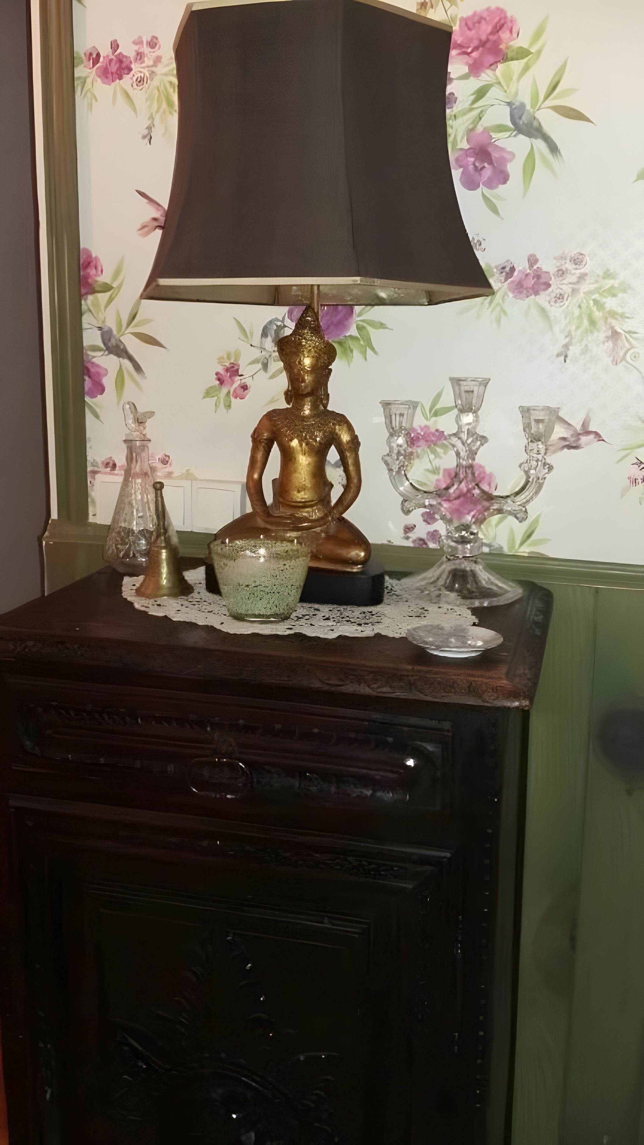 Une table avec une lampe, une figurine décorative et des objets en verre.