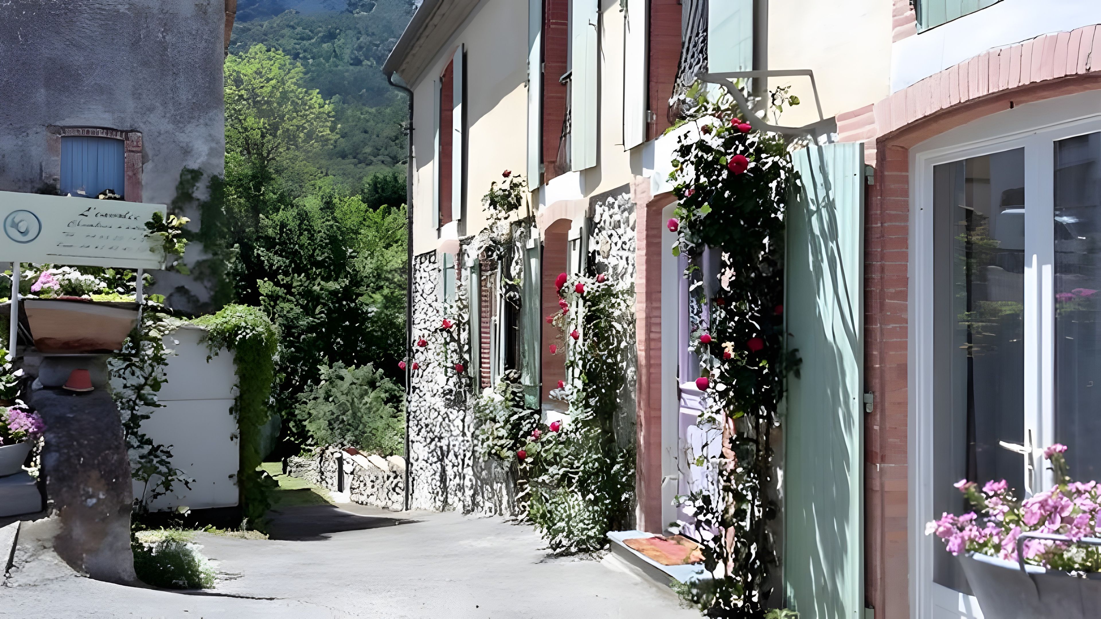 A narrow street with buildings on either side, some with flower boxes and greenery.