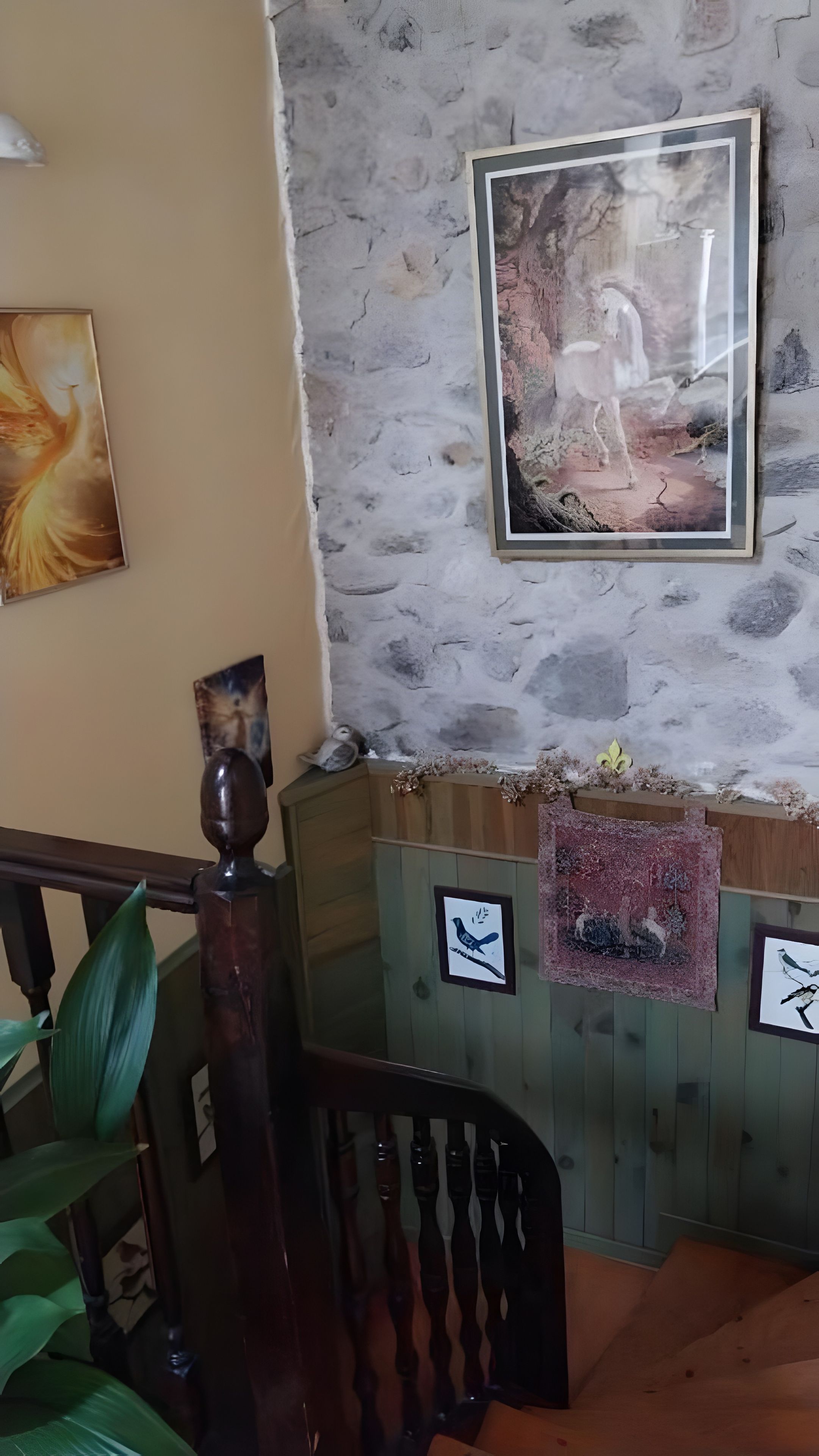 Una habitación con pared de piedra, un cuadro enmarcado y un banco de madera.