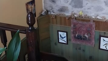 Una habitación con pared de piedra, un cuadro enmarcado y un banco de madera.