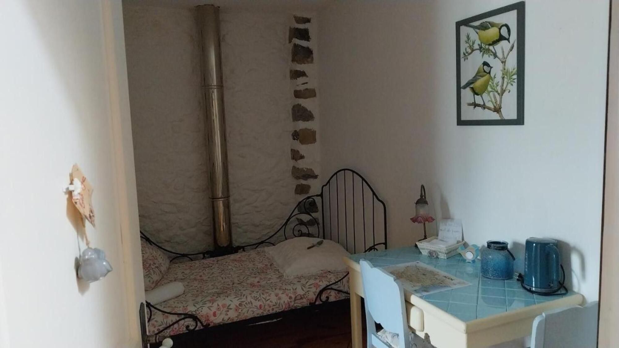 A bedroom with a bed, a nightstand, a lamp, and a framed picture on the wall.