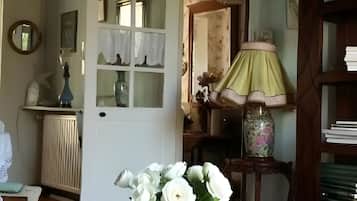 Une pièce avec une table, un vase de fleurs, une lampe et une bibliothèque.