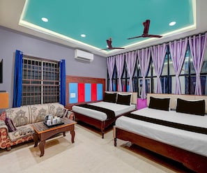 A hotel room with a sofa, two beds, a ceiling fan, and a window with curtains. - Deluxe Hotel Sunshine (Gop)