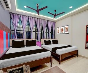 A hotel room with two beds, a ceiling fan, a window with purple curtains, and artwork on the wall. - Deluxe Hotel Sunshine (Gop)