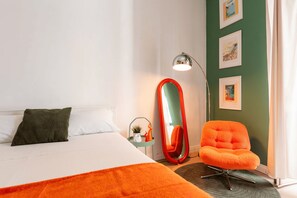 A hotel room with a bed, a chair, a mirror, and a lamp. - New Listing (Napoli)