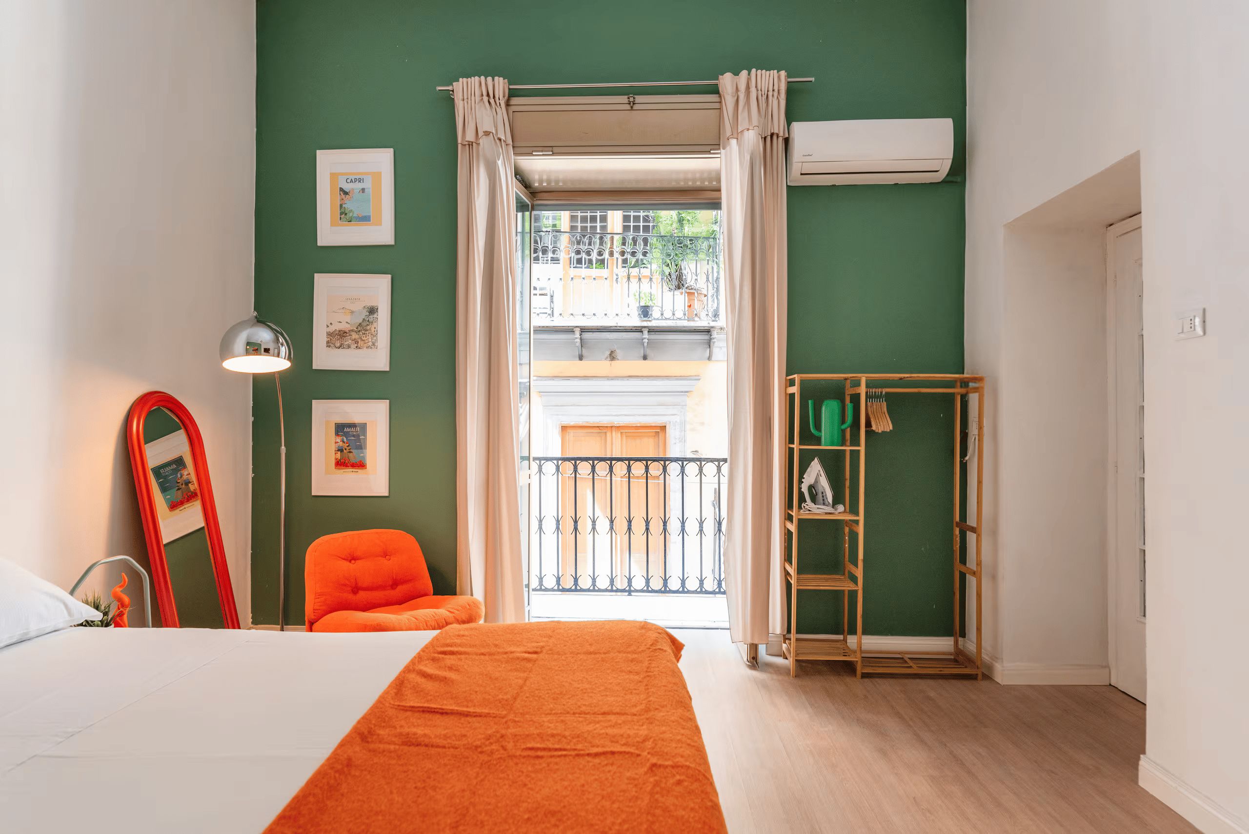 A bedroom with a bed, a chair, a wardrobe, and a balcony with a view.