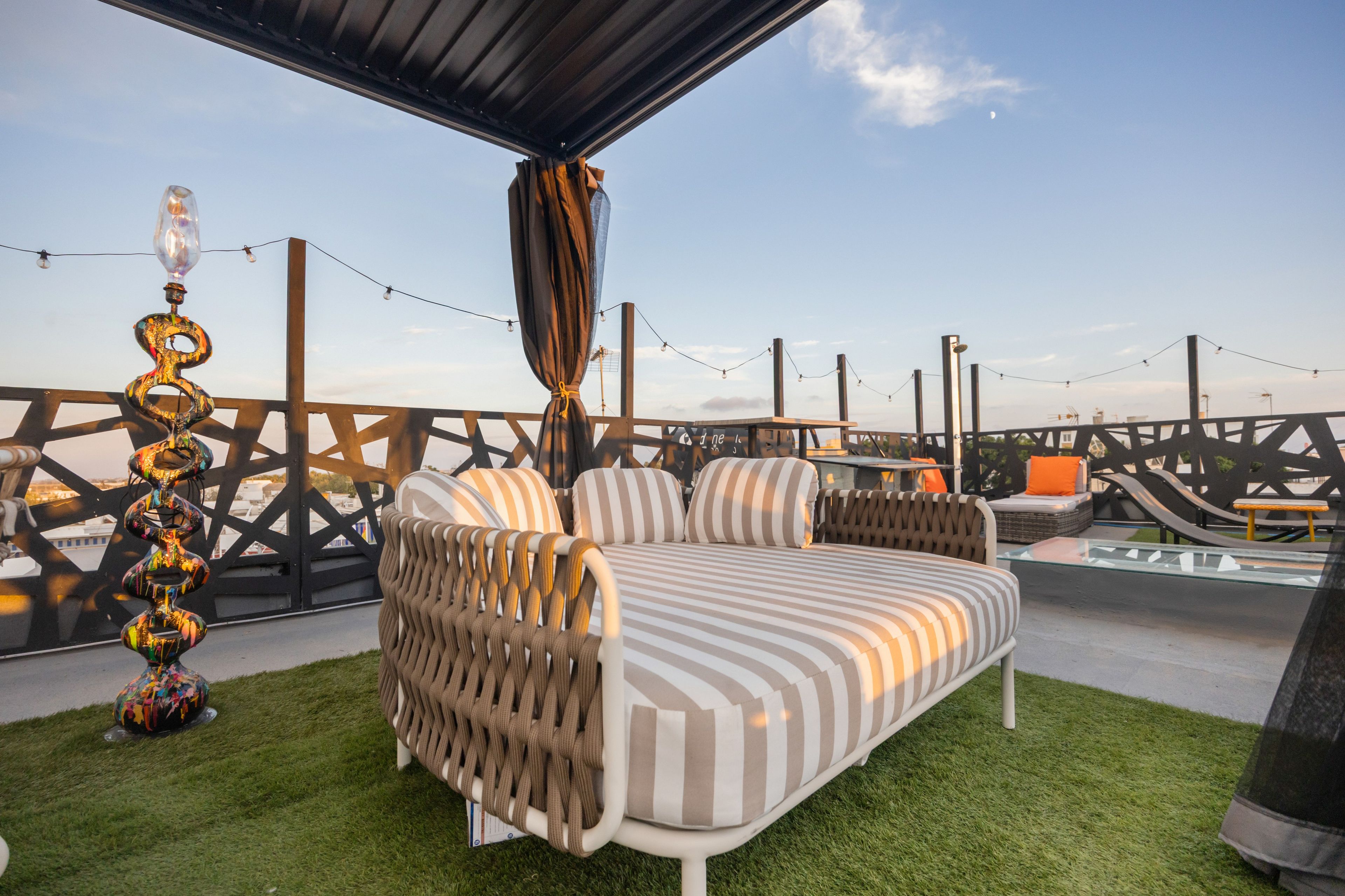 Een buitenzitplaats met een bank en stoelen, een decoratieve lamp en een uitzicht op de lucht.