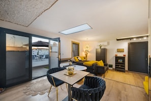 Un espacio habitable moderno con comedor, un conjunto de sofás y una pequeña cocina.