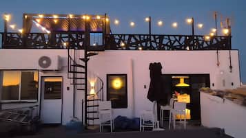 A rooftop terrace with string lights, a staircase, and a table with chairs.