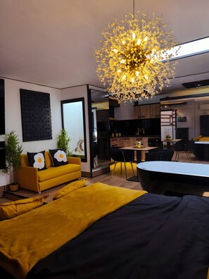 A modern living room with a yellow sofa, a black and yellow bed, a dining area, and a kitchen in the background. - Apartment 'Loft Margara' with Sea View, Wi-Fi and Air Conditioning (Chipiona)