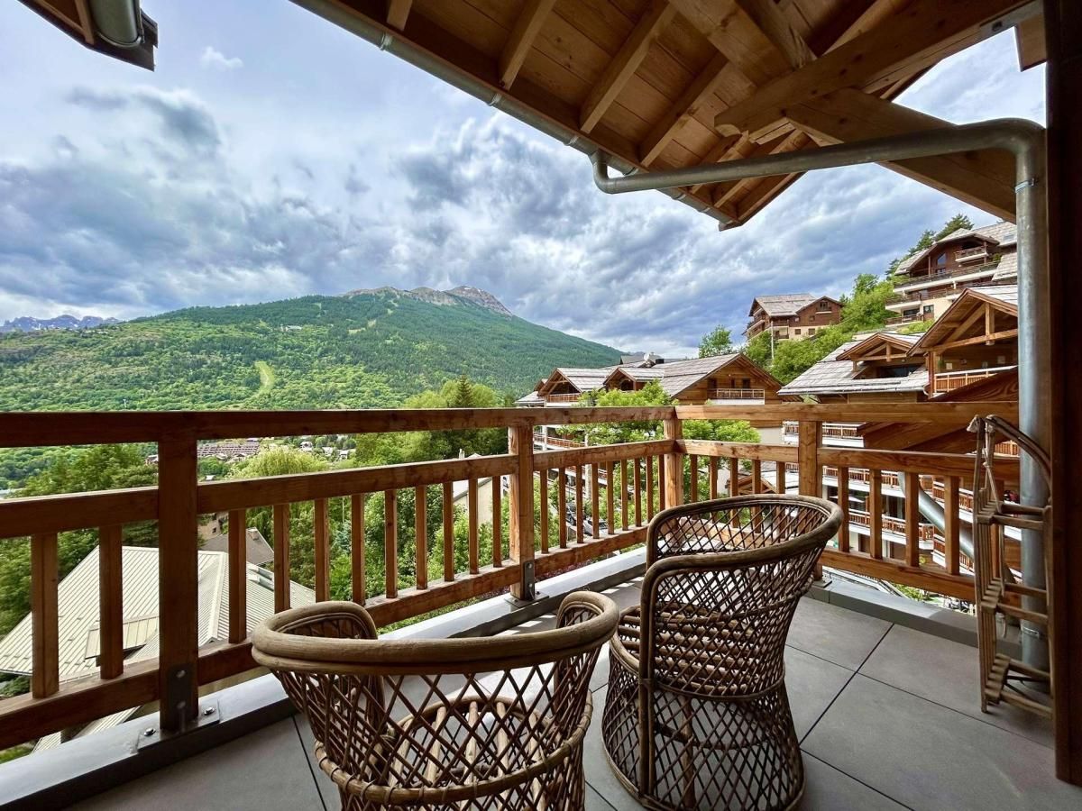 A balcony with wicker chairs overlooking a mountainous landscape.