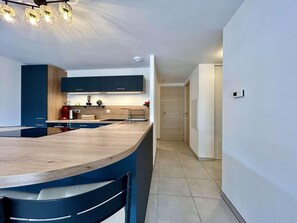 Una cocina moderna con una isla curva, electrodomésticos integrados y una paleta de colores neutros.