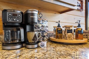 Una cafetera, un molinillo de café y un dispensador de cápsulas de café sobre una encimera de cocina.