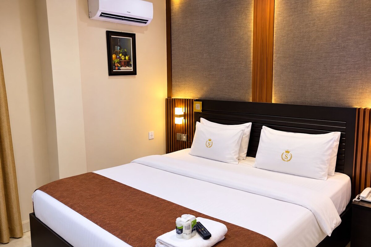 Ein Hotelzimmer mit einem Bett, einem Nachttisch mit Telefon, einem Bild an der Wand und einer Klimaanlage.