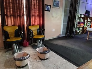 Ein Zimmer mit zwei gelb-schwarzen Stühlen, einem kleinen Tisch und zwei Fußmassagegeräten auf dem Boden.