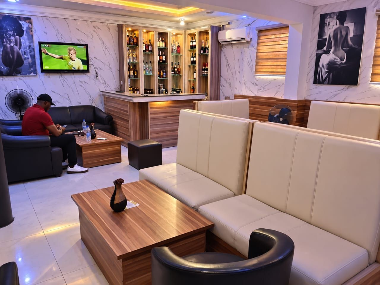 A modern lounge area with a bar, seating, and a television.