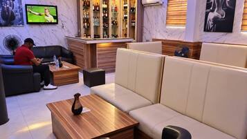 A modern lounge area with a bar, seating, and a television.