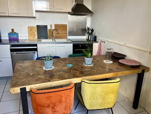 A kitchen with a wooden table, two chairs, a dishwasher, and a stainless steel range hood. - New Listing (Bordeaux)