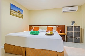 A hotel room with a bed, a nightstand, a wardrobe, and an air conditioning unit. - IslaRita Stays #6 spacious studio near Eagle Beach (Oranjestad)