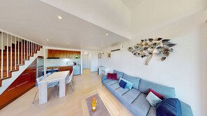 Un apartamento moderno con una escalera, un comedor, una sala de estar con sofá y una cocina.