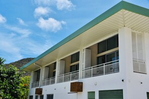 Un edificio moderno con techo plano, varios balcones con barandillas metálicas y ventanas amplias.