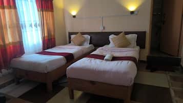 A hotel room with two single beds, a wooden headboard, a red and white checkered floor, and a bathroom door.
