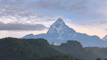 A mountain landscape with a prominent peak, lush green hills, and a small building on the left.