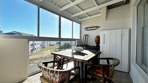 A room with a table and chairs, a view of the outside, and a sign that reads 'Each House'. - Perfect 2-bedroom apartment in Big Bay with stunning views (Cape Town)