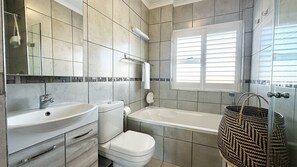 A bathroom with a sink, toilet, and bathtub. - Perfect 2-bedroom apartment in Big Bay with stunning views (Cape Town)