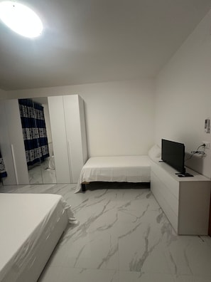 A bedroom with a bed, a TV, a dresser, and a wardrobe. - New Listing (Venezia)