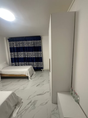 A bedroom with a bed, a bedside table, a mirror, and a window with curtains. - New Listing (Venezia)