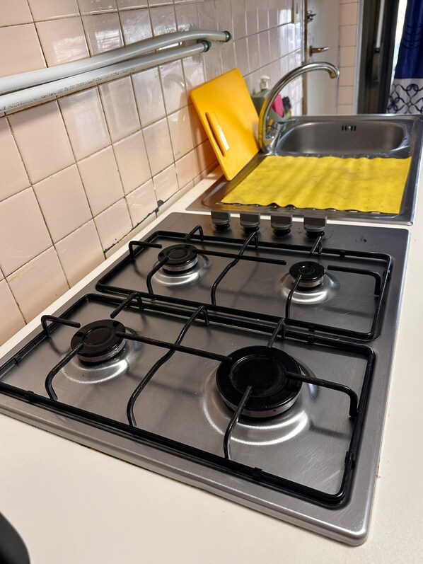 A kitchen with a gas stove, a yellow sponge, and a stainless steel sink. - New Listing (Venezia)