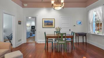 A dining area with a wooden table and chairs, a chandelier, and a painting on the wall.