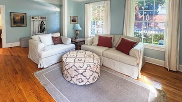 A living room with two sofas, a patterned ottoman, a lamp, and a ceiling fan.