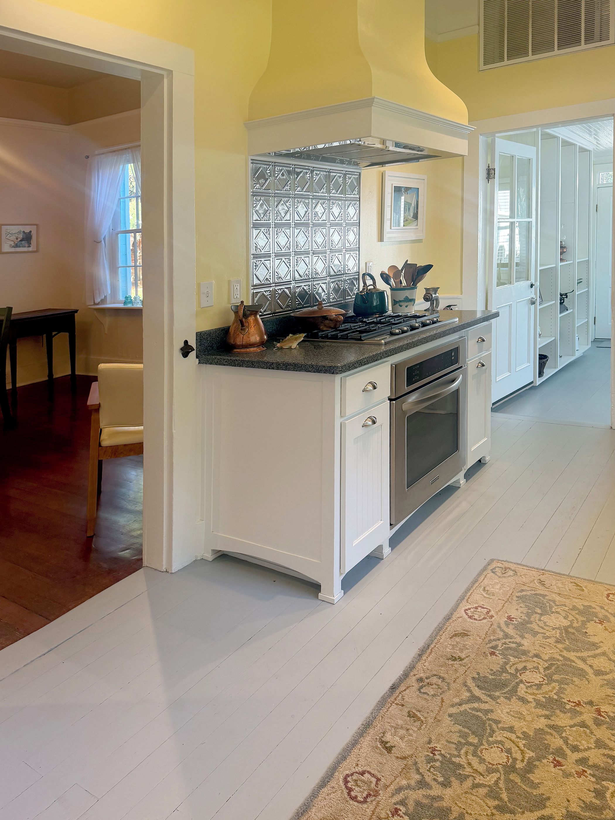 A kitchen with white cabinetry, a stove, and a window with a decorative screen.