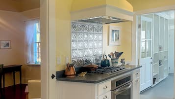 A kitchen with white cabinetry, a stove, and a window with a decorative screen.
