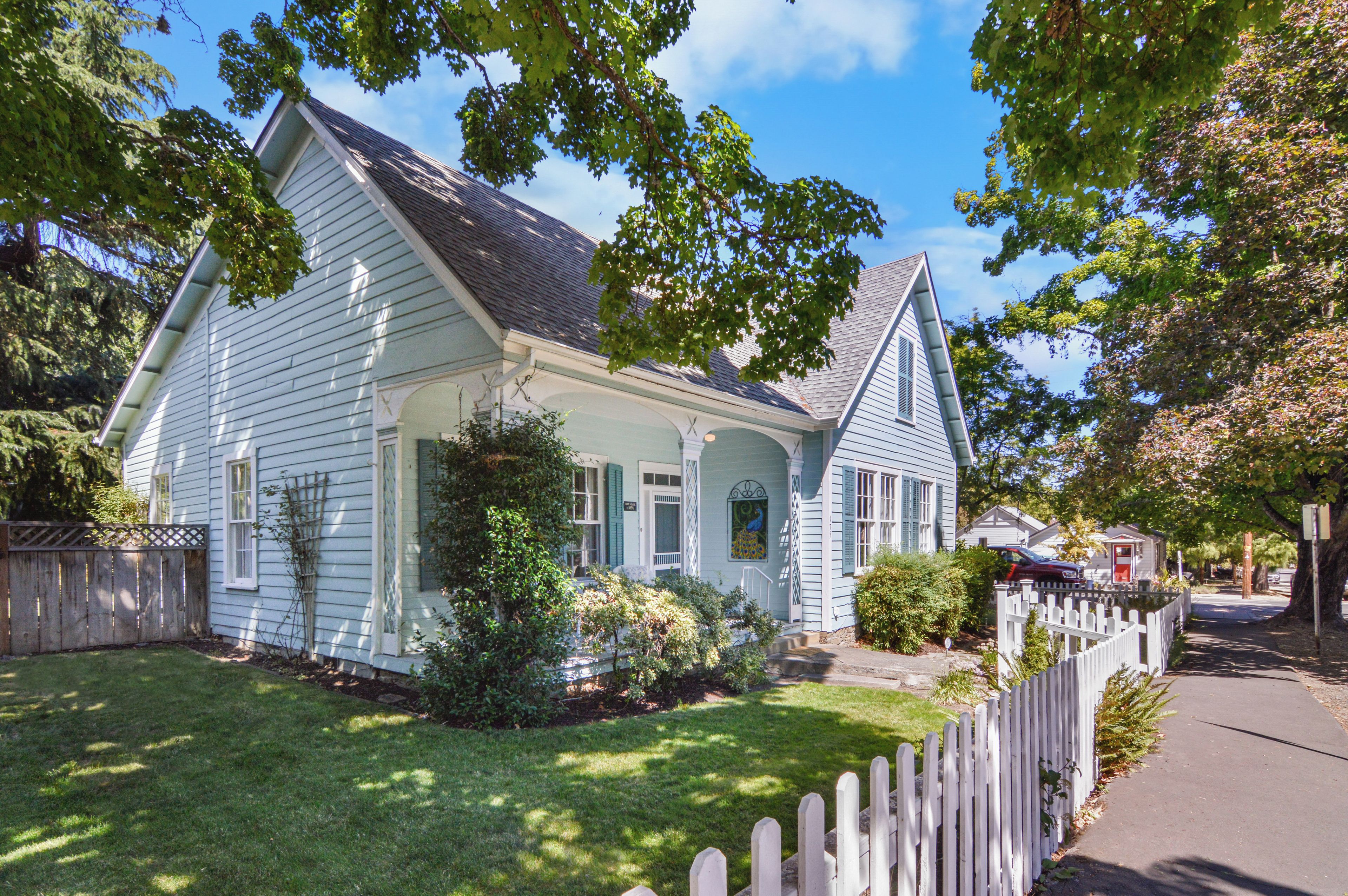A single-story house with a gabled roof, a front porch, and a picket fence.