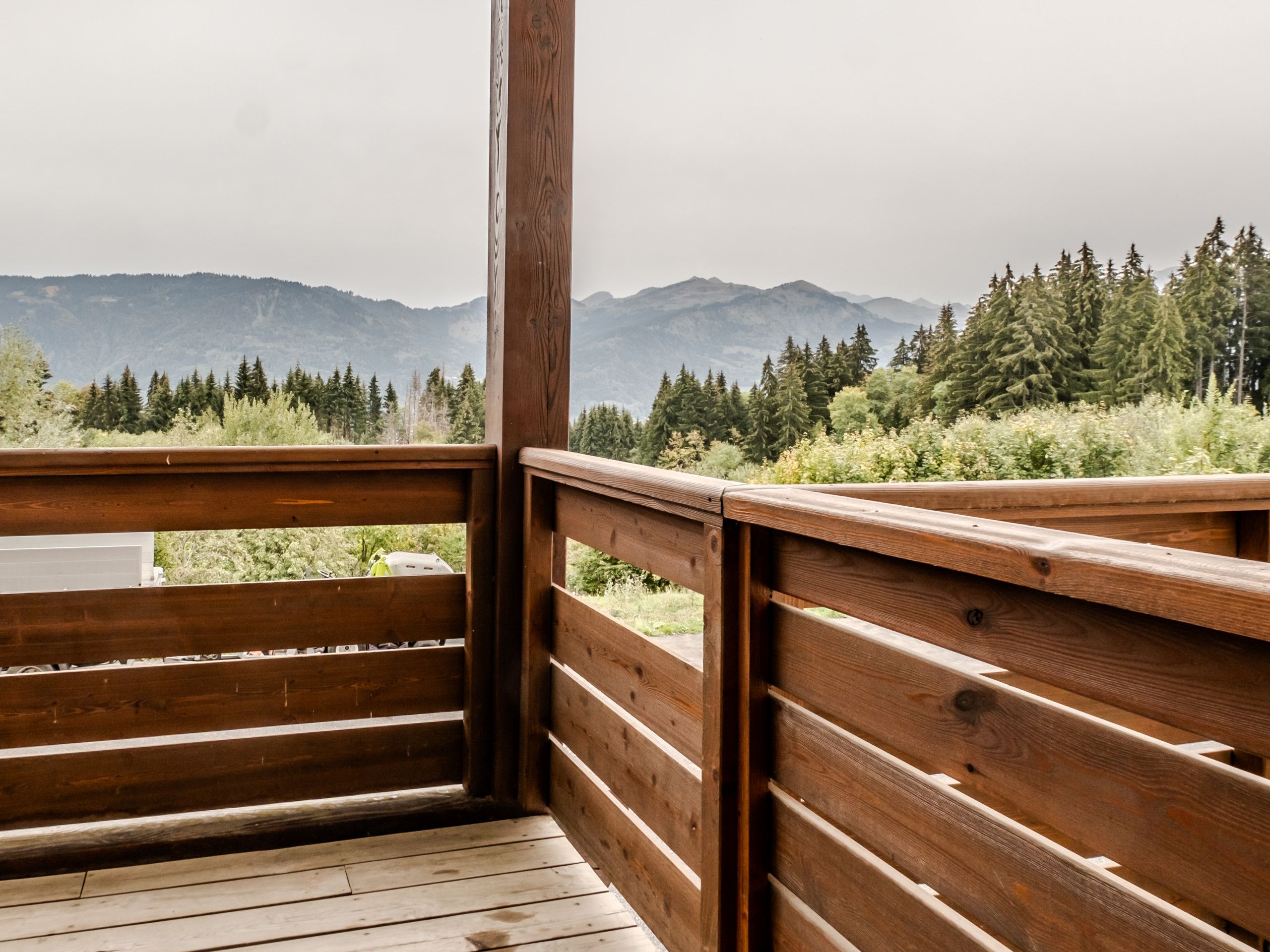 A wooden deck with a view of a forest and mountains.