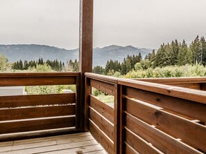 A wooden deck with a view of a forest and mountains. - Apartment with balcony with mountain view (Morillon)