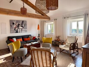 A living room with a sofa, chairs, a coffee table, a lamp, and a window with curtains. - Room 'Chambre Foulque - Double Deluxe' with Wi-Fi and air conditioning (Portiragnes)