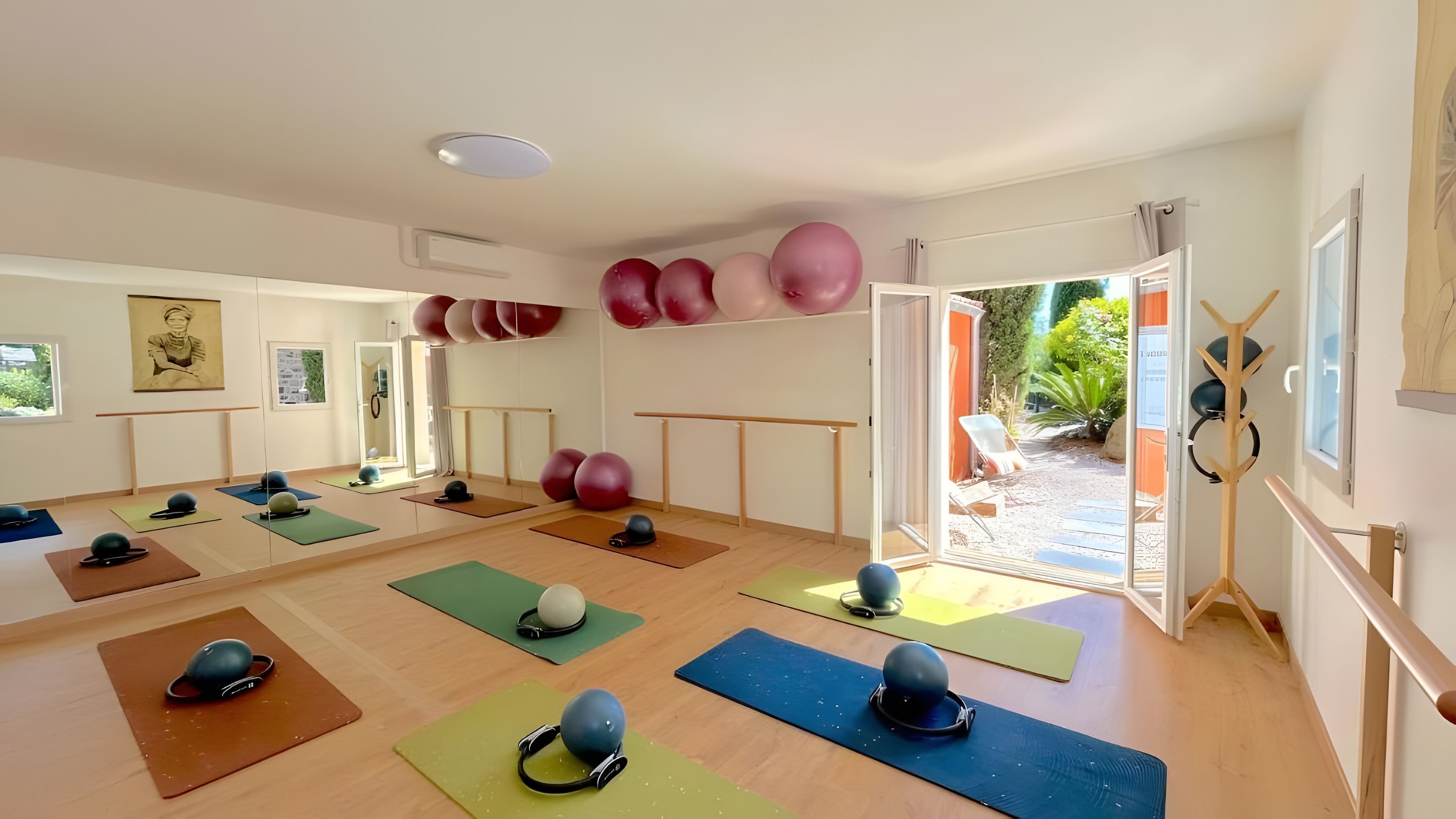 Een yogastudio met matten, oefenballen en een houten barre.