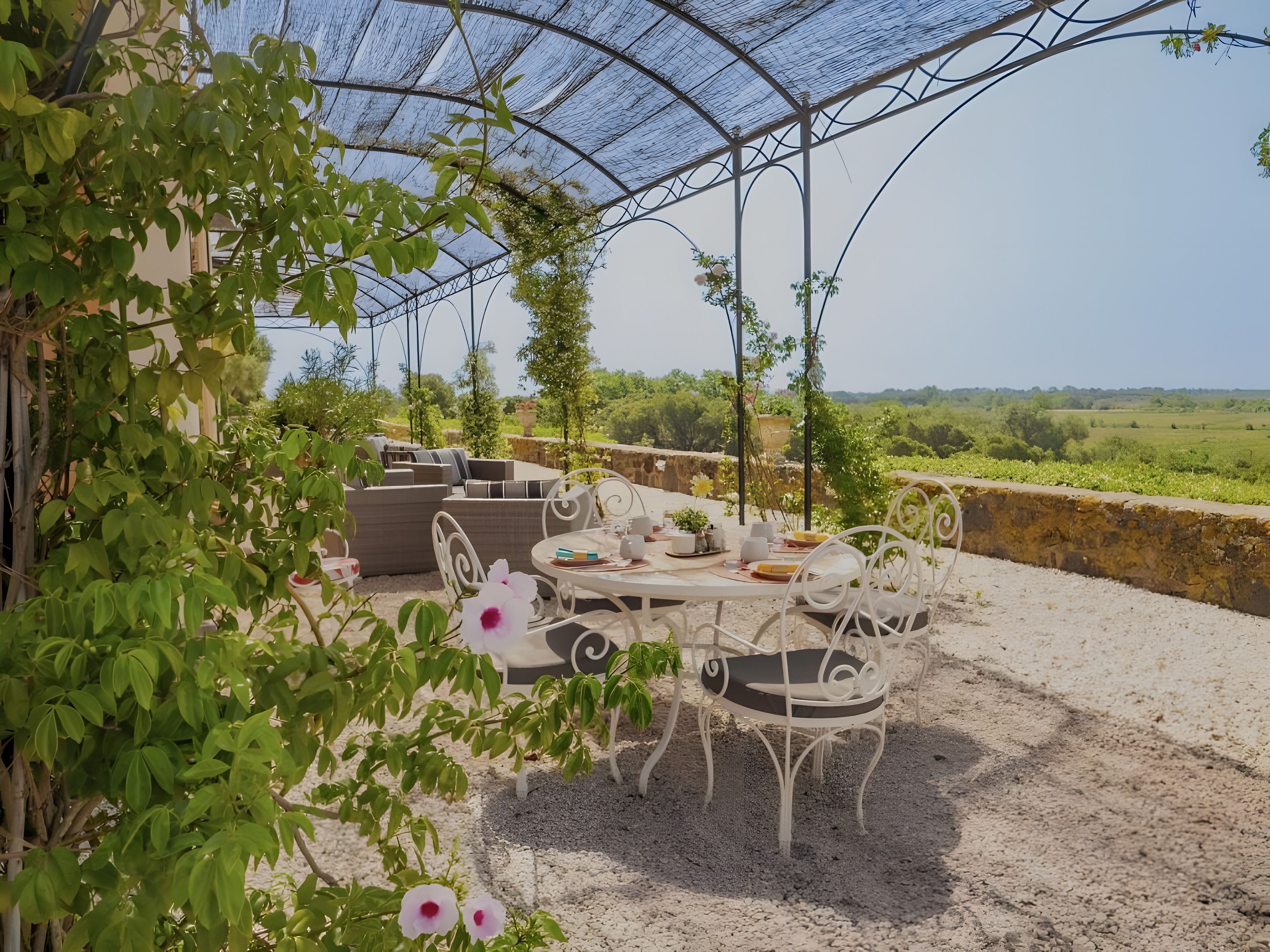 Een terras met een eettafel, omringd door groen en uitzicht op het platteland.