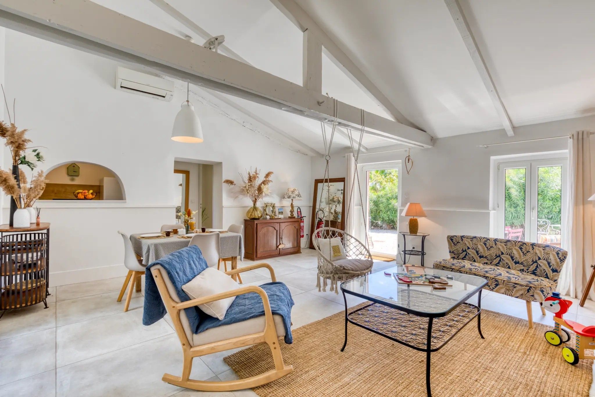 A spacious living room with a high ceiling, a dining area, and a sofa.