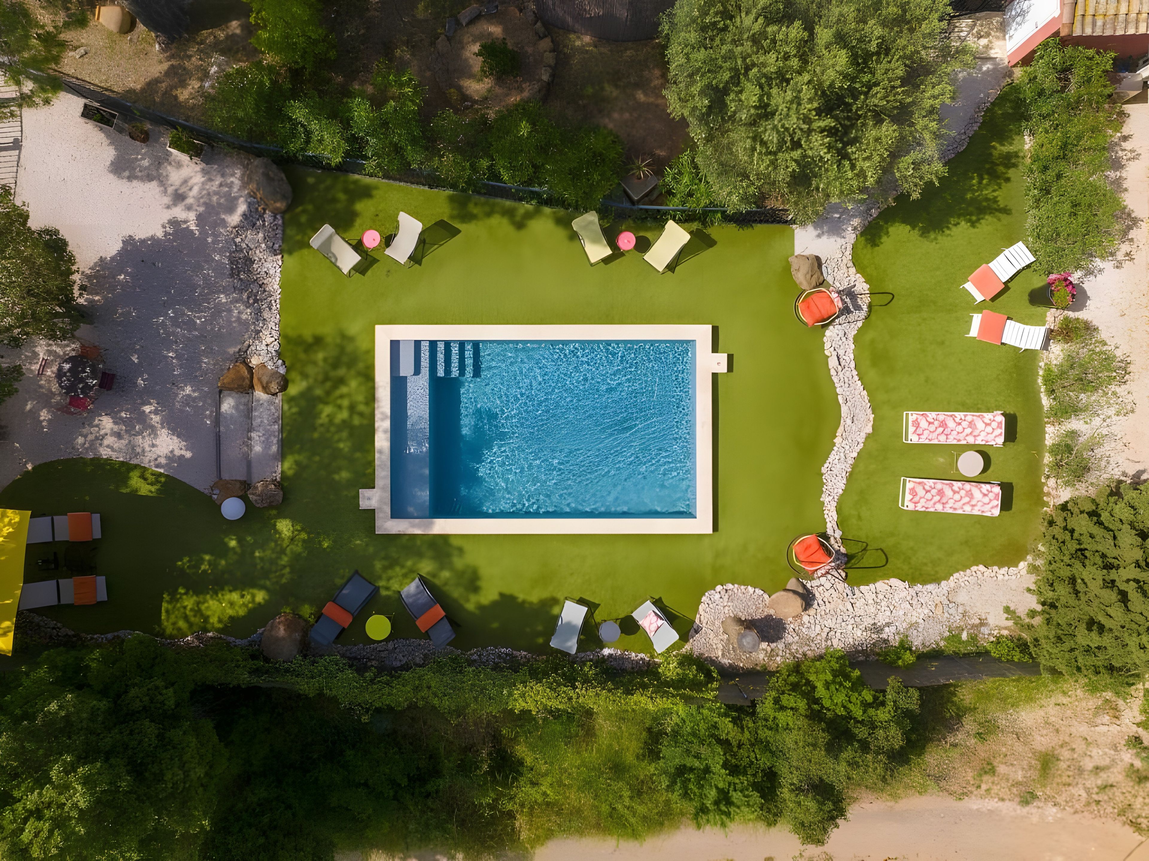 An aerial view of a swimming pool surrounded by lounge chairs and a small deck area.