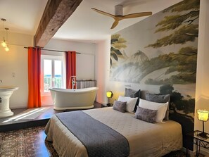 Quarto moderno com uma cama grande, banheira e um mural de paisagem montanhosa.