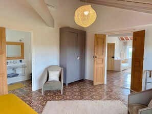 A spacious room with a patterned floor, a wooden wardrobe, a chair, and a hanging light fixture. - Apartment 'Suite Grand Duc - Vue Mer' with Wi-Fi and Air Conditioning (Portiragnes)