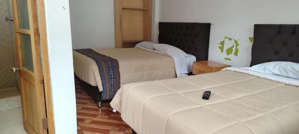 A hotel room with two beds, a wooden wardrobe, and a small bedside table.